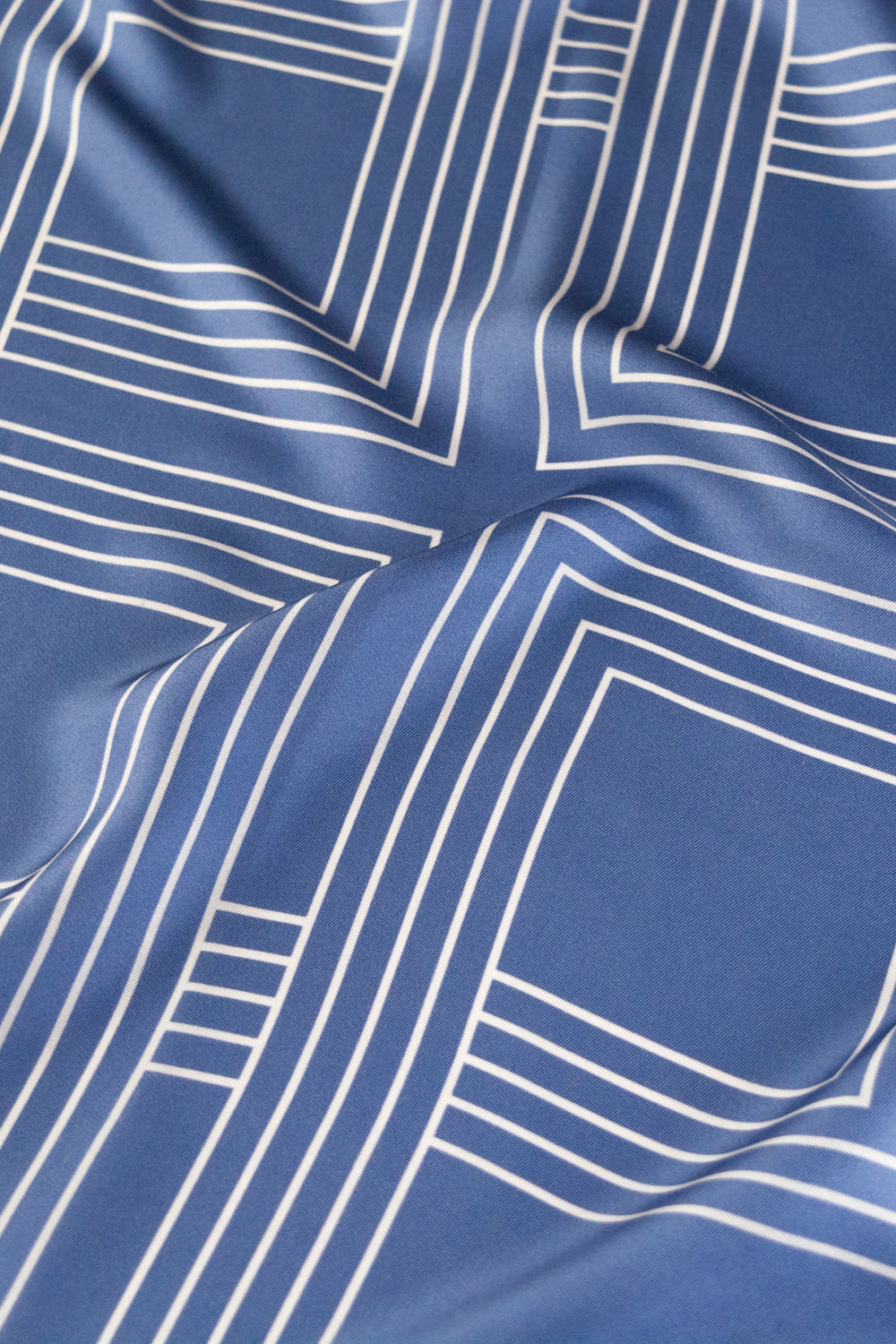 Detailaufnahme eines blauen Seidentuchs mit weißem Quadratmuster.