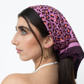 Model trägt ein Seidentuch mit Leopardenmuster in Lila- und Orangetönen als Kopftuch.
