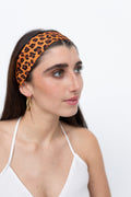 Weibliches Model trägt ein Seidentwilly mit braunem Leopardenmuster als Haarband gebunden.