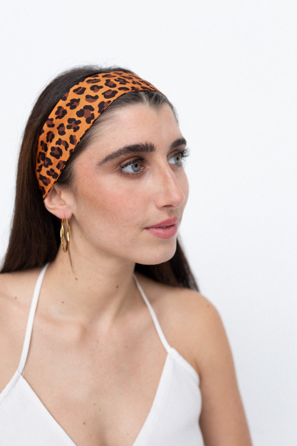 Weibliches Model trägt ein Seidentwilly mit braunem Leopardenmuster als Haarband gebunden.