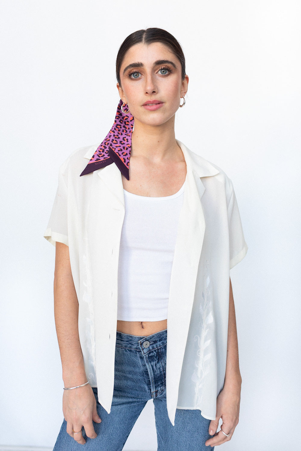 Weibliches Model trägt einen Seidentwilly mit lila Leopardenmuster im Haar gebunden.