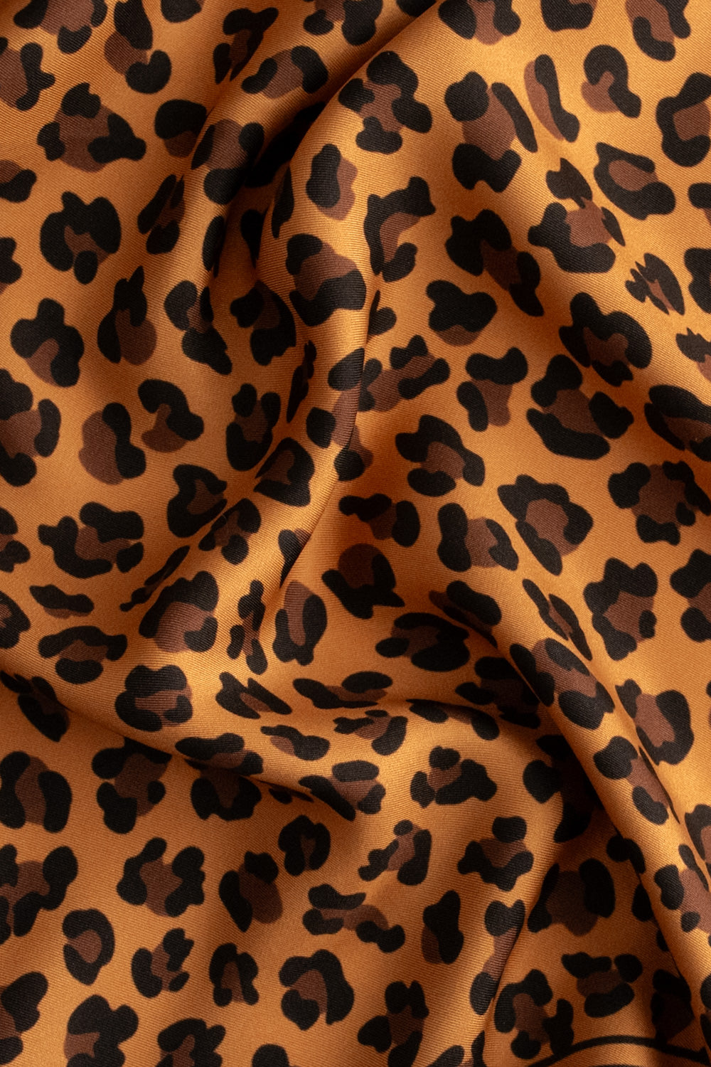 Detailaufnahme eines Seidentuchs mit braunem Leopardenmuster.