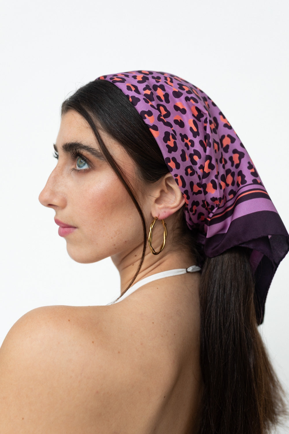 Weibliches Model trägt ein Seidentuch mit lila Leopardenmuster, als Kopftuch.