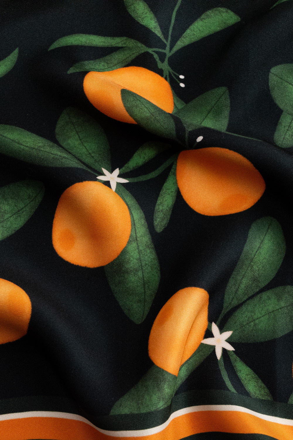 Detailaufnahme eines schwarzen Seidentuchs mit Orangenprint.
