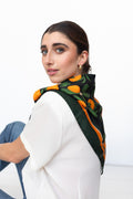 Model trägt ein schwarzes Seidentuch mit Orangenprint über den Schulter.