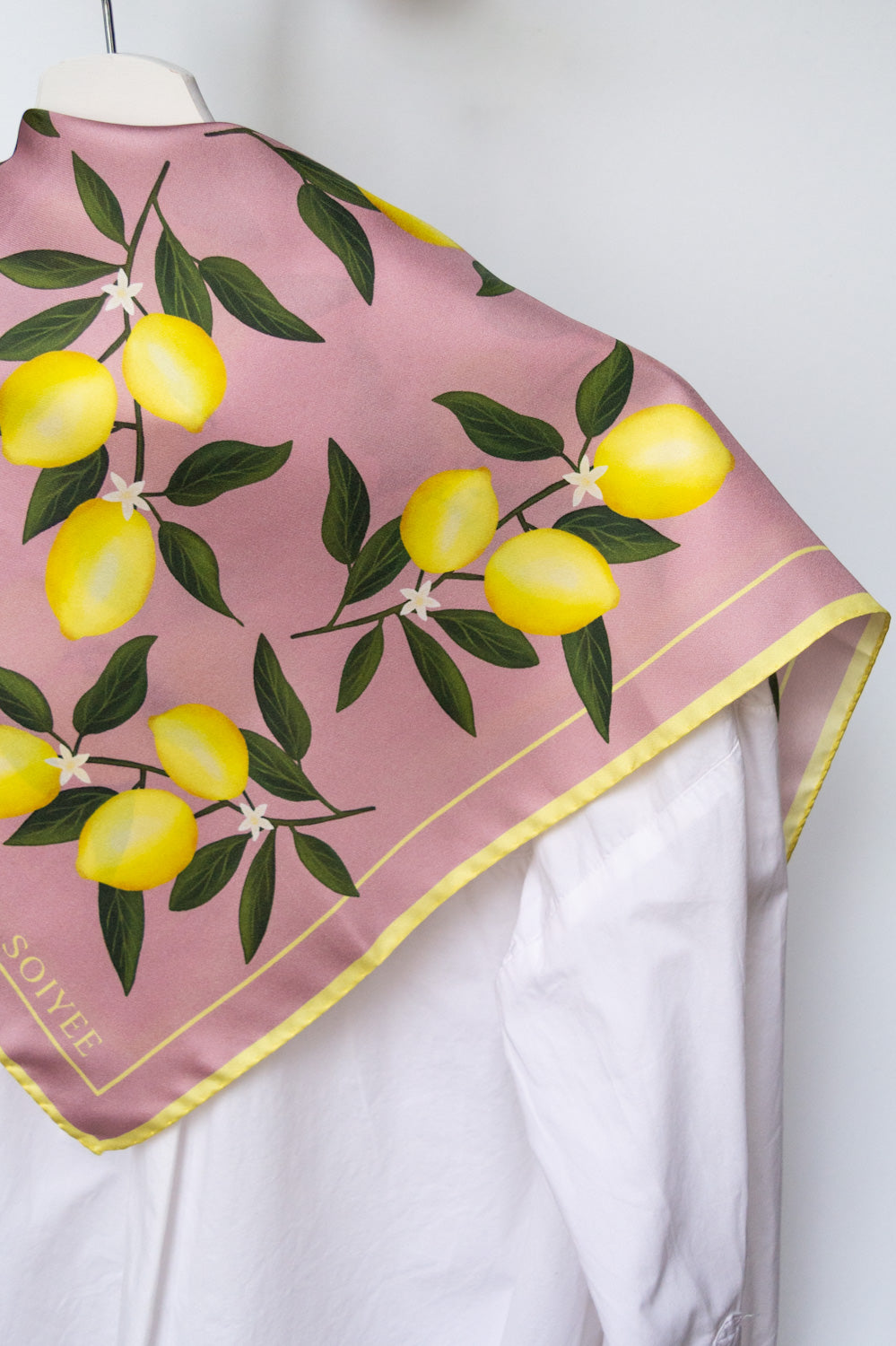 Rosa Seidentuch mit Zitronenprint auf weißer Bluse.